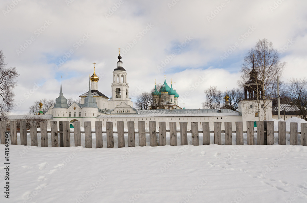 A view of the Tolga convent from the side of the Volga River. In the foreground there is snow and a wooden fence.