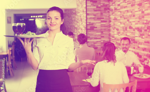 young woman waiter bringing order for guests