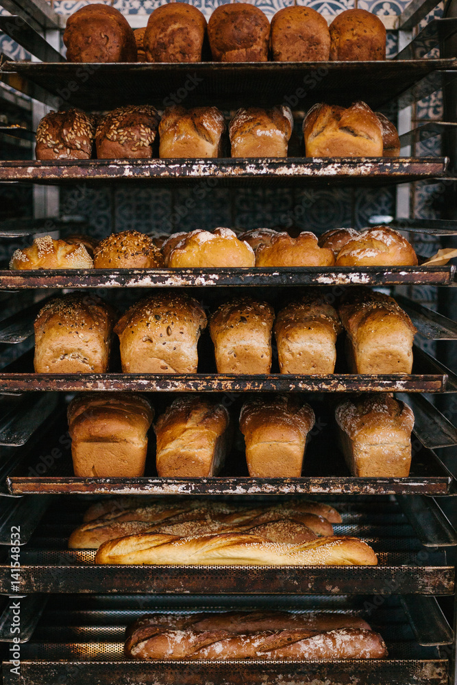 A lot of ready-made fresh bread in a bakery oven in a bakery. Bread making business. Fresh bread from cereals with seeds from a bakery. Healthy and nutritious food. The product contains carbohydrates.