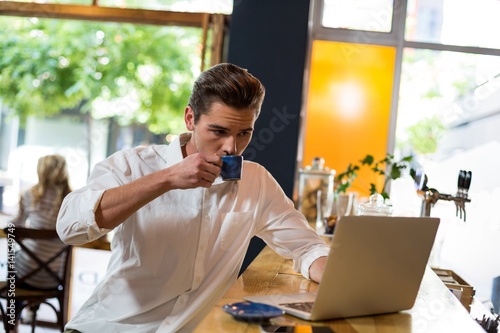 Man having coffee while using laptop