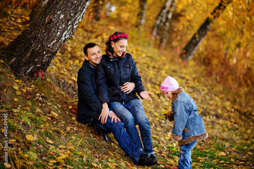 Parents look at children in autumn park © cezarksv
