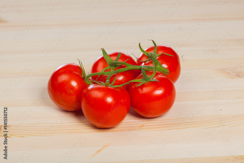 organic red tomatoes with the stem on the wood table organic red tomatoes with the stem on the wood table