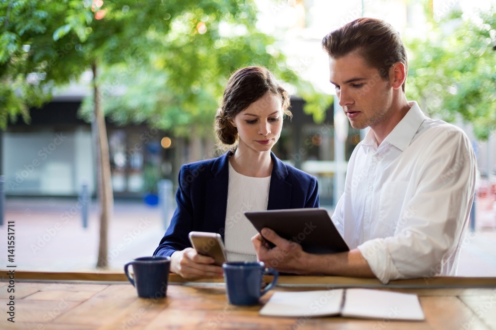 Businesspeople discussing over digital tablet at counter Businesspeople discussing over digital tablet at counter