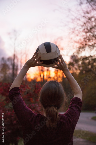 Teenage boy throwing ball at sunset photo