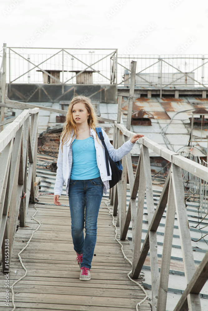 girl walks with a blue backpack on the roof