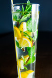 Close up Glass of lemonade with mint and lemon wedges on the dark background. Selective focus