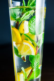 Close up Glass of lemonade with mint and lemon wedges on the dark background. Selective focus