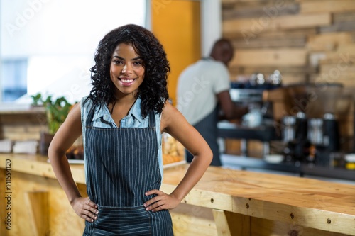 Portrait of smiling waitress with hands on hip 