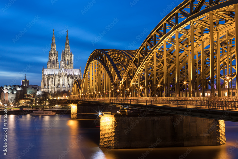 Naklejka premium Illuminated Hohenzollern Bridge And Cologne Cathedral At Sunset / Germany