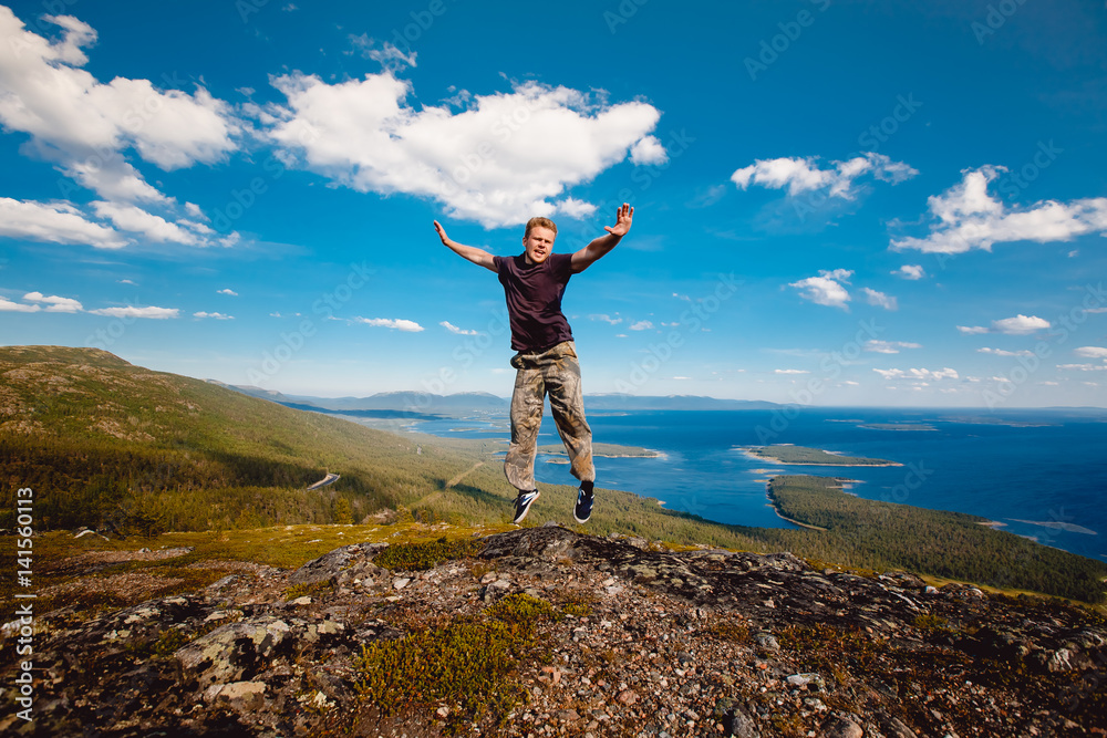 Obraz premium Male tourist man sitting jumping on a mountain on a white sea background. Kandalaksha, Murmansk region, the Kola Peninsula, Russia.