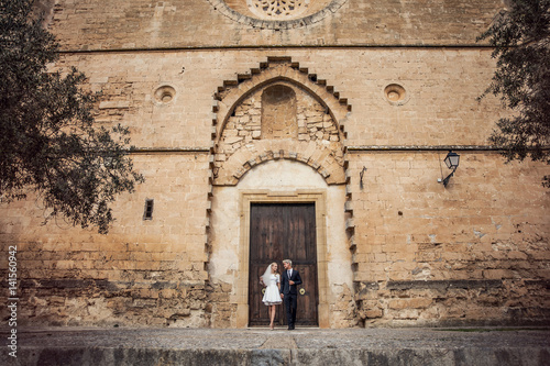 Fashionable wedding couple near Catholic church. Bride and Groom. Outdoor portrait © indigolt