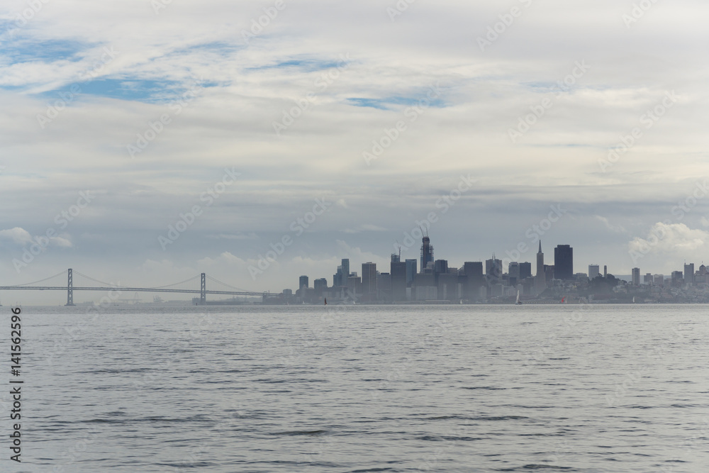 A cloudy sunset over the San Francisco bay seen from a boat on the water. Views of the city and golden gate bridge