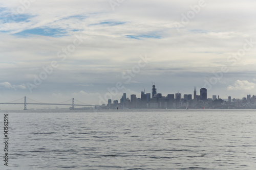 A cloudy sunset over the San Francisco bay seen from a boat on the water. Views of the city and golden gate bridge