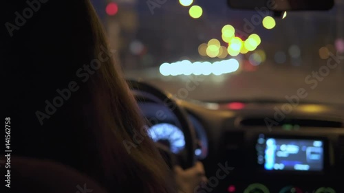 A young woman is driving a car in the night city