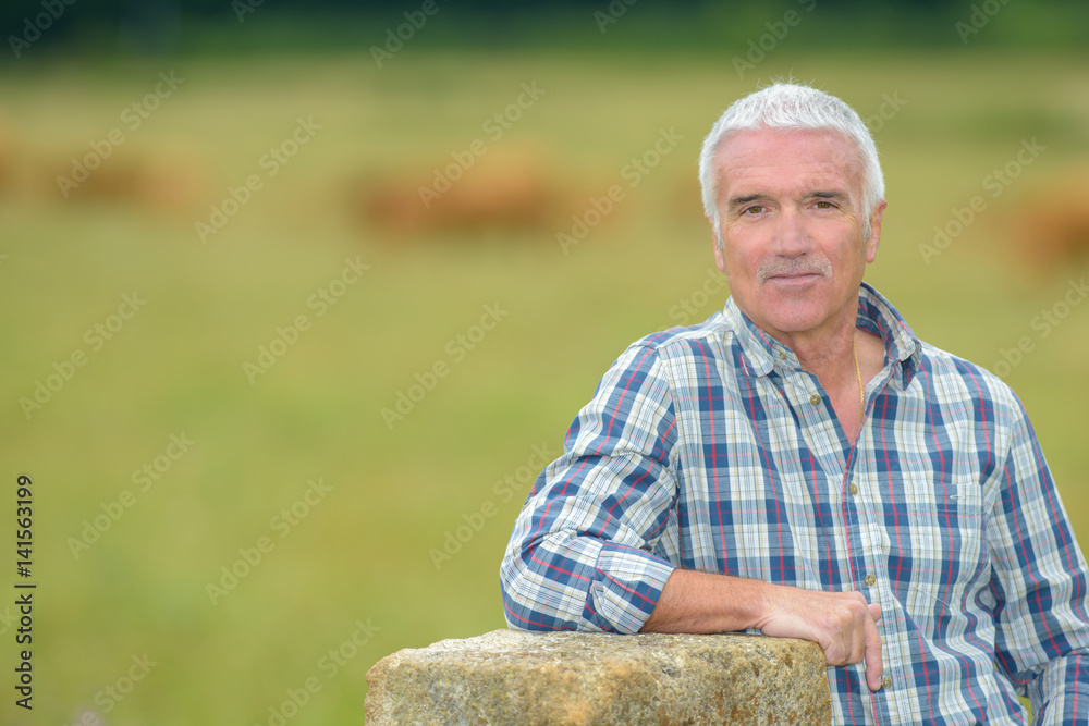 Portrait of senior man leaning on bale of hay Portrait of senior man leaning on bale of hay