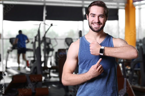 Handsome young man with fitness tracker in gym
