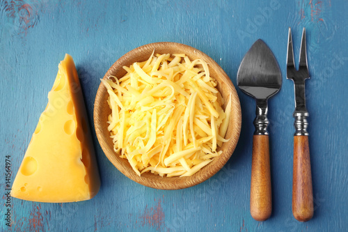 Bowl with grated cheese on blue textured background