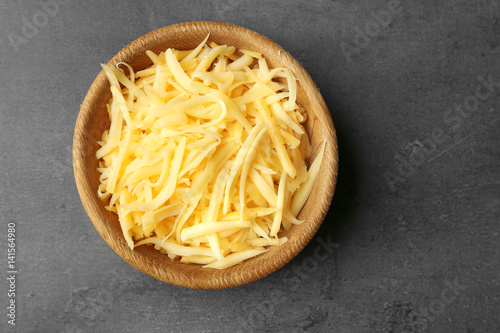 Bowl with grated cheese on dark background