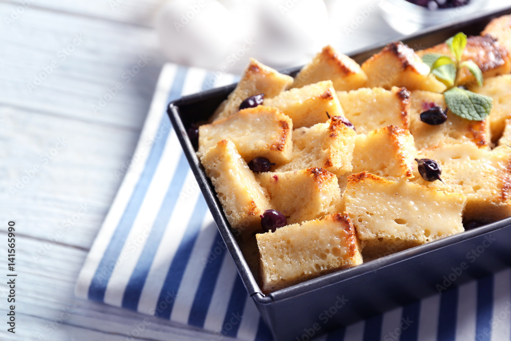 Delicious bread pudding with currant in baking dish on kitchen table