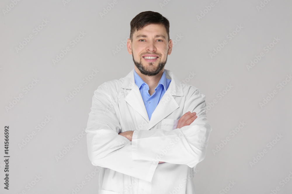 Young handsome pharmacist with crossed arms on grey background Young handsome pharmacist with crossed arms on grey background