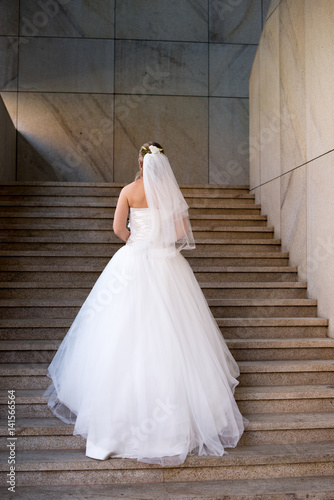 Attractive charming bride in a white dress standing on ladder © Alex