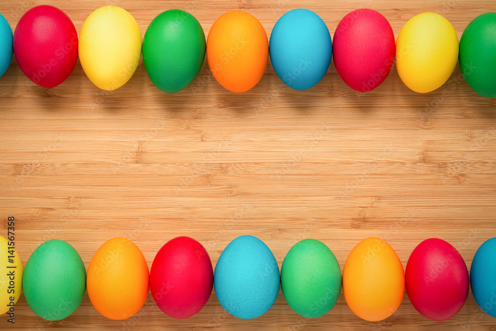 Multicolored easter eggs on a light wooden background. Eggs on top and bottom in a row. The concept of a holiday and a happy Easter. Place for text Multicolored easter eggs on a light wooden background. Eggs on top and bottom in a row. The concept of a holiday and a happy Easter. Place for text