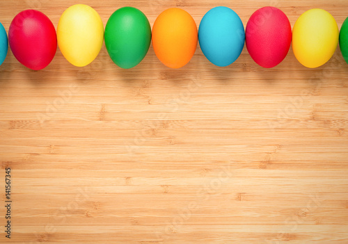 Multicolored easter eggs on a light wooden background. Eggs from the top in a row. The concept of a holiday and a happy Easter. Place for text