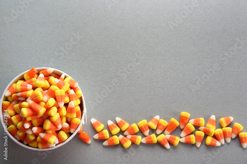 Bucket with tasty Halloween candies on light background