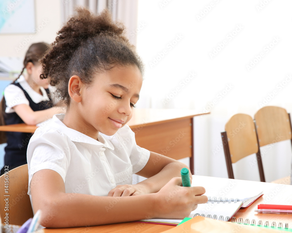 Beautiful elementary schoolgirl studying in classroom Beautiful elementary schoolgirl studying in classroom