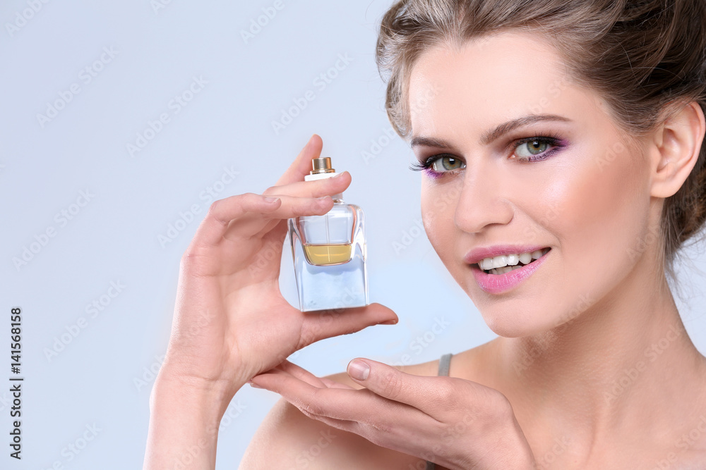 Beautiful young woman with bottle of perfume on color background Beautiful young woman with bottle of perfume on color background