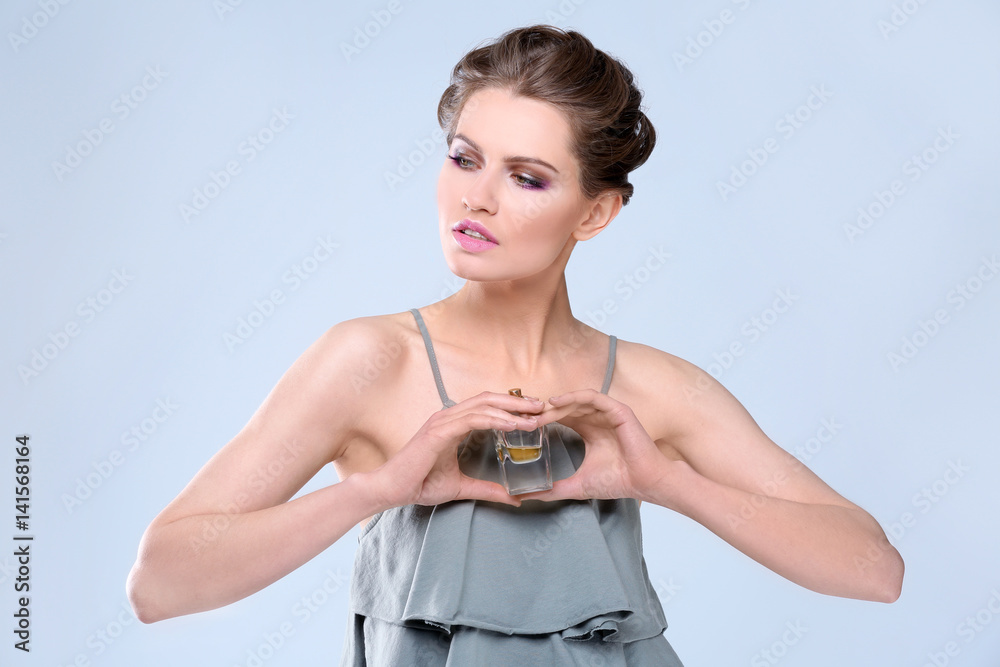 Beautiful young woman with bottle of perfume on color background Beautiful young woman with bottle of perfume on color background