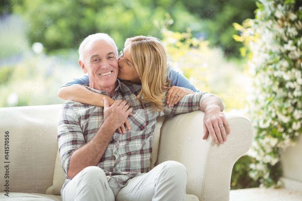 Senior woman kissing man on cheek in living room Senior woman kissing man on cheek in living room