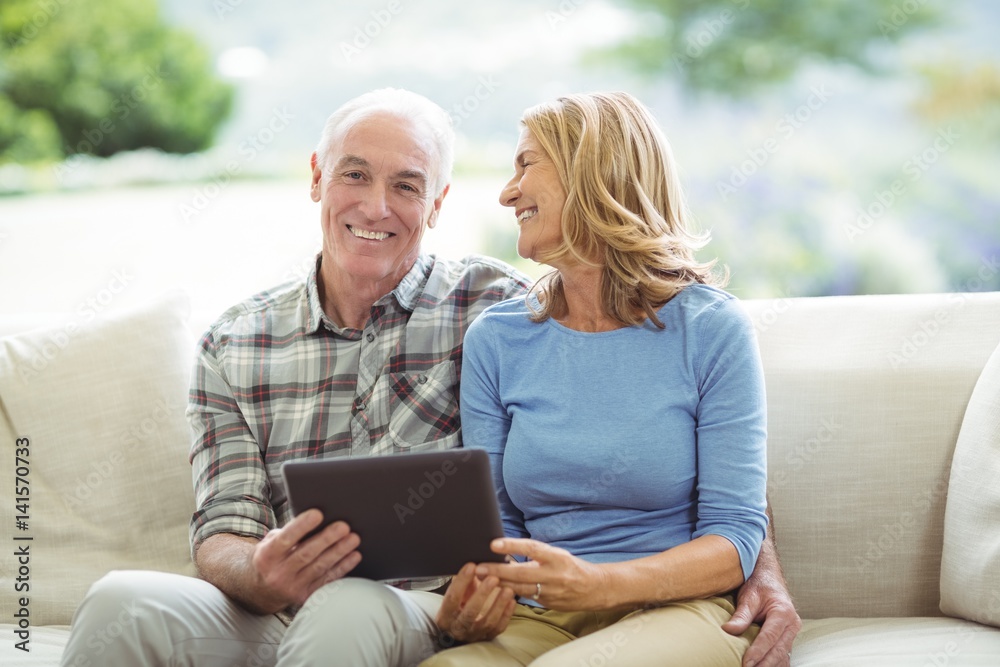 Smiling senior couple sitting on sofa Smiling senior couple sitting on sofa
