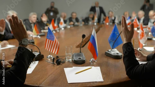 Delegation of Russian Federation at international summit. Russian participant of global economic conference. Politicians cheer the speaker. Diverse audience raise hands and vote for bill. First-person