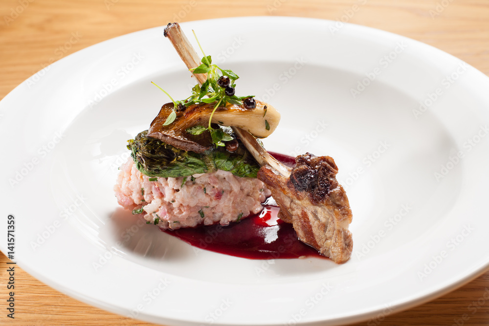 Lamb rib chop with raspberry risotto, cabbage rolls and blackberry sauce.