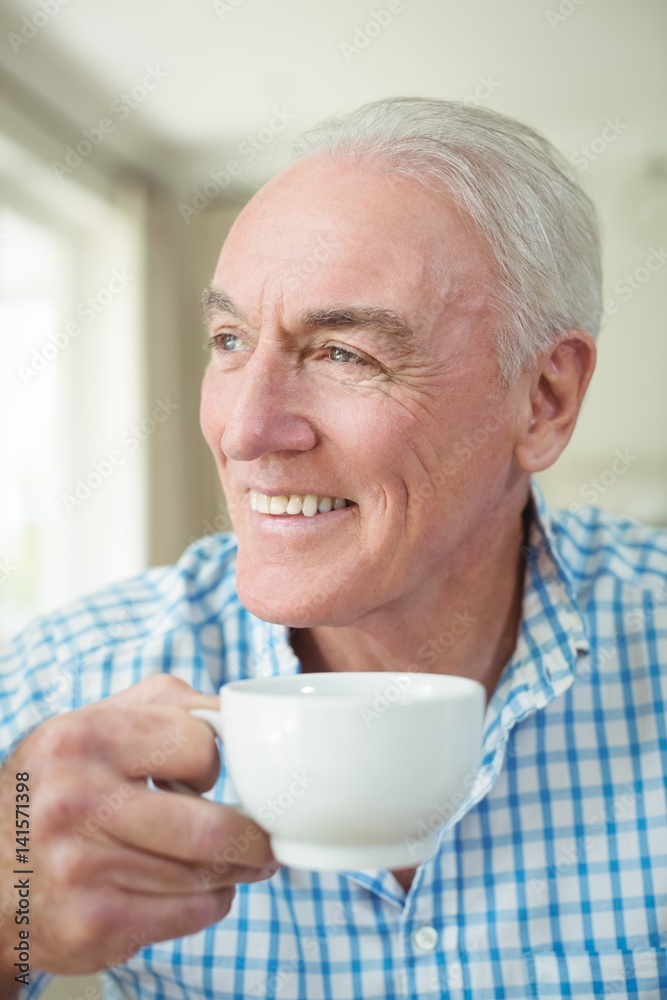Smiling senior man having cup of coffee in living room Smiling senior man having cup of coffee in living room