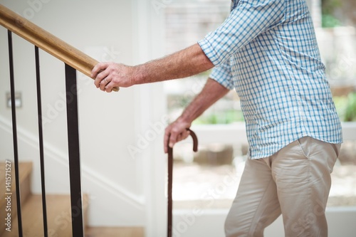 Фотография Senior man climbing upstairs with walking stick