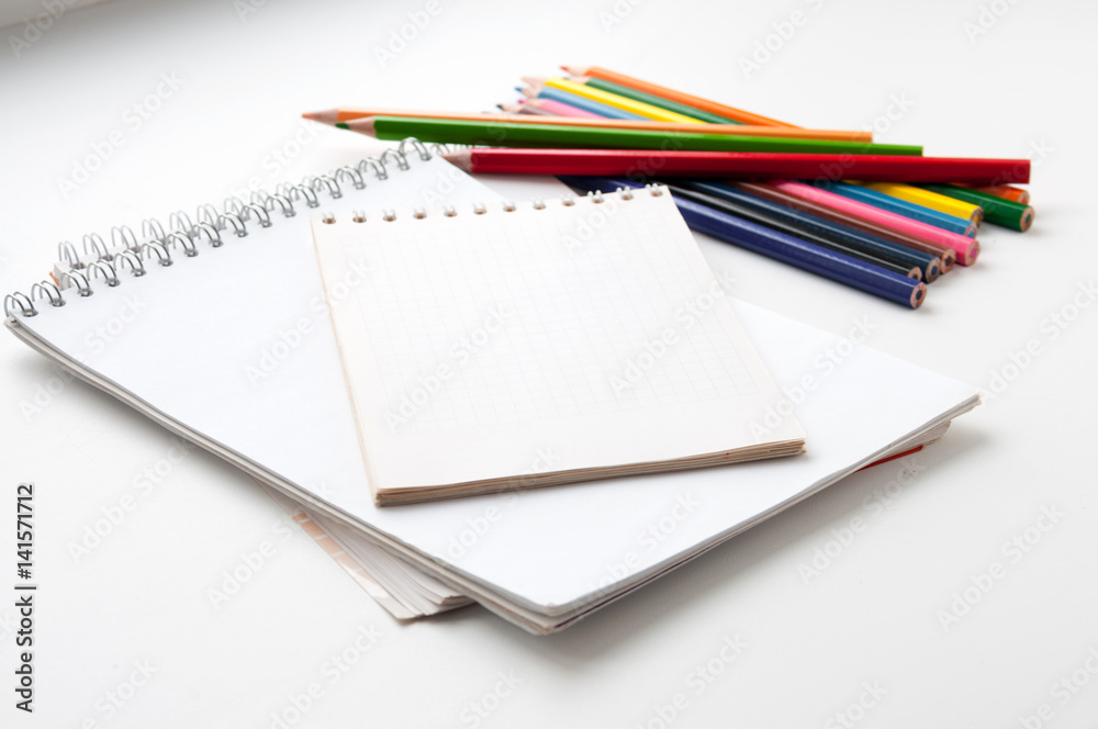 Notepad and colored pencils on a light background Notepad and colored pencils on a light background
