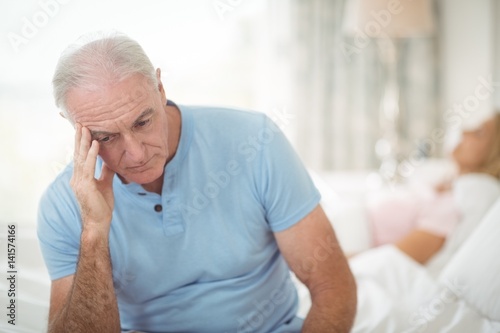 Worried senior man sitting in bedroom