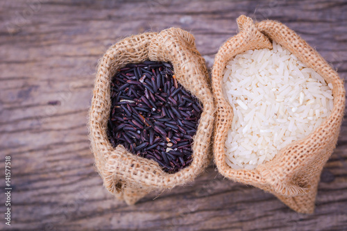 Black rice and Raw grain white rice in burlap bag on wood background,Jasmine rice,