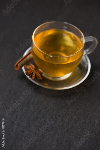 Cup of black tea with spices on white wooden background.