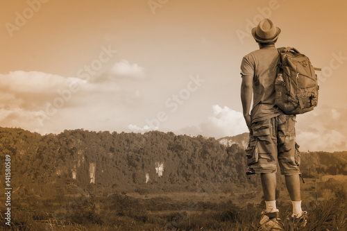 Man Asian backpack standing on the rock and looking mountain background.Back of man.Tone