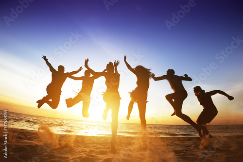 Happy friends jumps beach sunset. Friendship or team concept