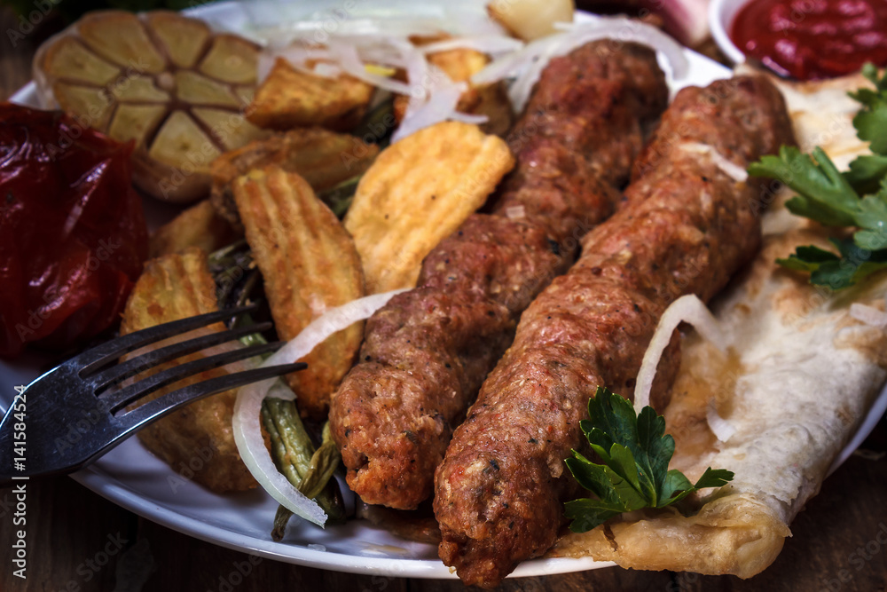 Fried kebab kebab with vegetables grilled sauce, onion and spices. Barbecue. Still life. Rustic. Closeup Fried kebab kebab with vegetables grilled sauce, onion and spices. Barbecue. Still life. Rustic. Closeup