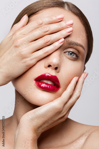 Beautiful young model with red lips and nude manicure