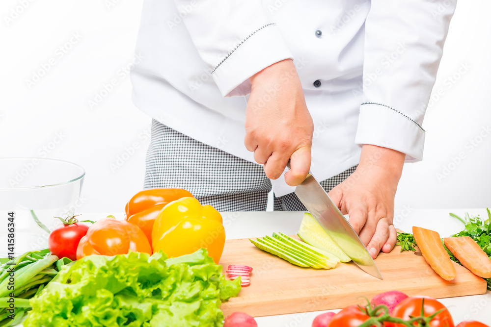 Chef cuts salad, prepares fresh vegetables on white background Chef cuts salad, prepares fresh vegetables on white background