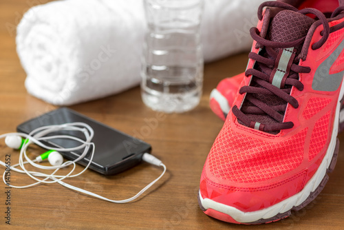closeup of running shoes and mobile phone headphones on a dark wooden floor