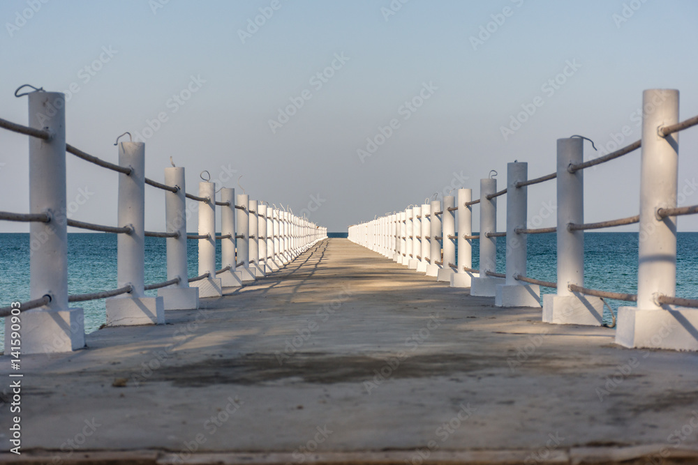 White posted concrete jetty leading out to a calm sea. White posted concrete jetty leading out to a calm sea.