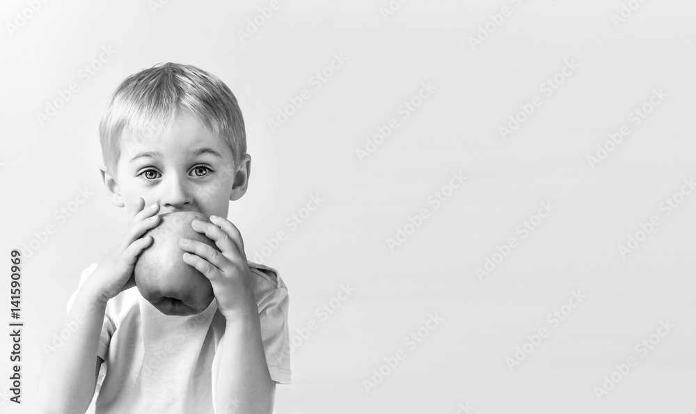 Happy cheerful boy eats the big apple, the child is the fruit green, soft focus Happy cheerful boy eats the big apple, the child is the fruit green, soft focus
