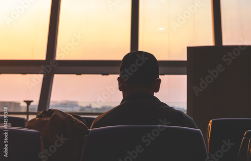 A man waring cap sitting and waiting for the flight in the airport, ready for departure,